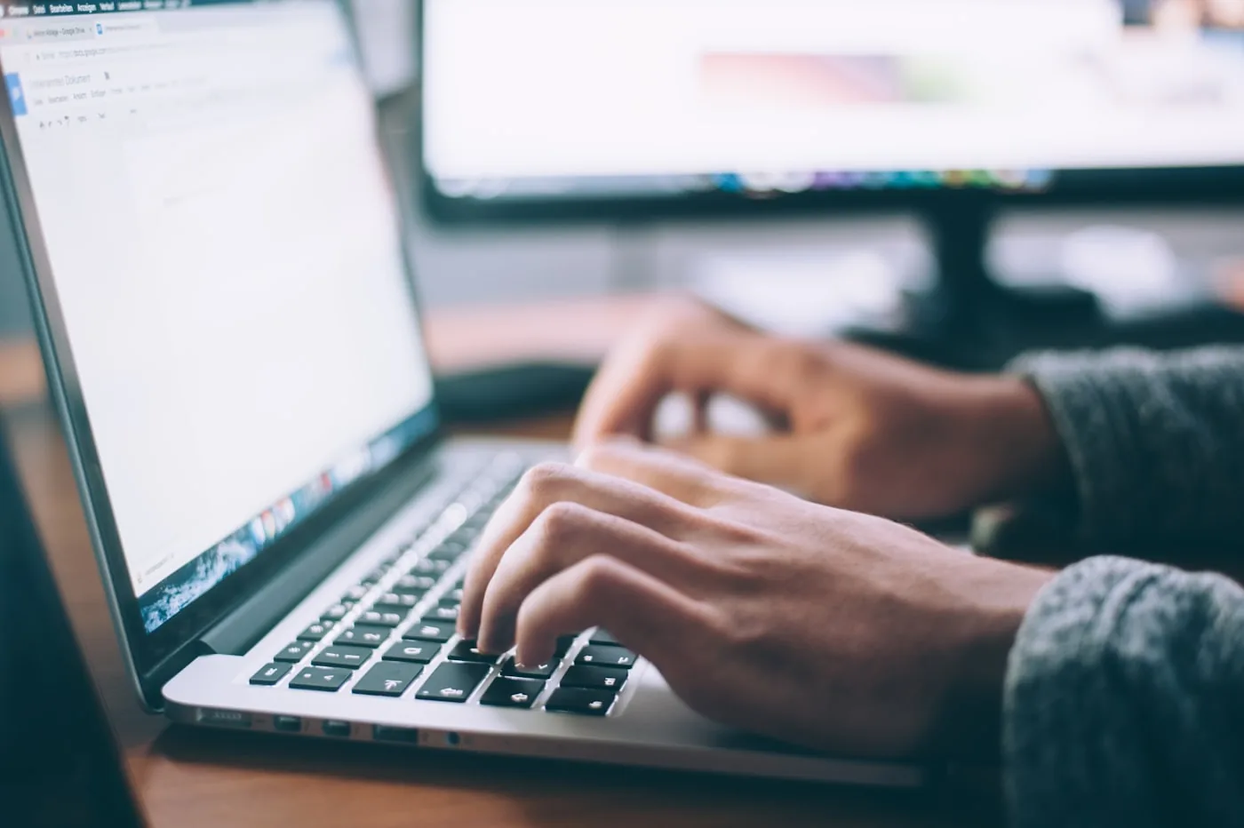 Handen op een laptoptoetsenbord tijdens het schrijven van een e-mail